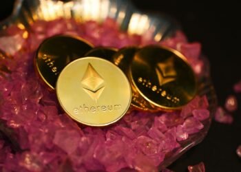 Gold Ethereum coins on pink crystals, illustrating an Ethereum price prediction