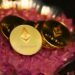 Gold Ethereum coins on pink crystals, illustrating an Ethereum price prediction