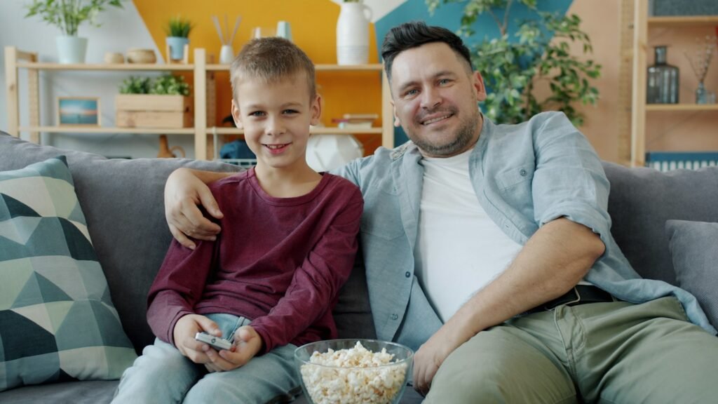 Father and son sharing popcorn during a movie night on the couch