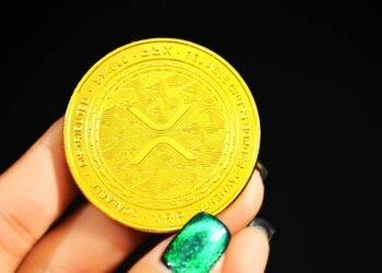 Gold XRP coin held in a hand, illustrating an XRP price prediction