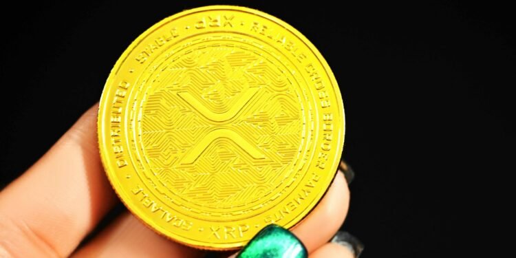 Gold XRP coin held in a hand, illustrating an XRP price prediction
